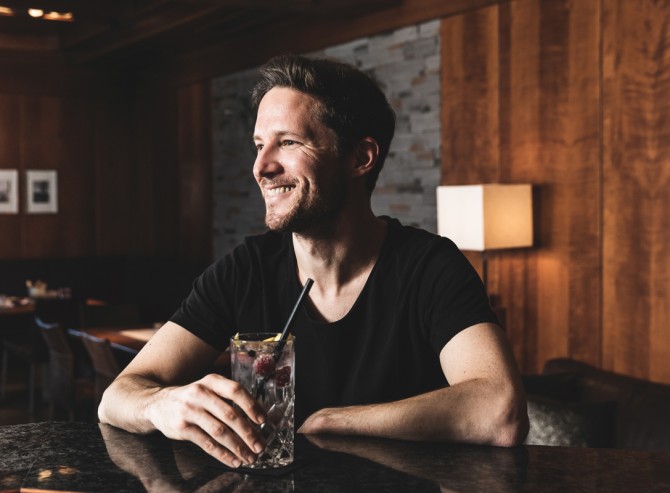 Mann mit seinem Cocktail an der Bar im Hotel Montanara